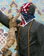 En amerikansk marinesoldat placerer det amerikanske flag på hovedet af en statue af Saddam Hussein, før statuen væltes i april 2003 efter den amerikansk-anførte invasion. Arkivfoto. 