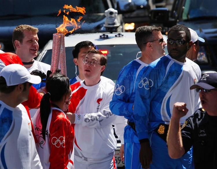 Fakkelbærere overdrager den olympiske ild til hinanden i San Fransisco i går. På trods af protester over hele verden opfordrer IOC-chef Jacques Rogge OL-alteterne til at bevare troen på OL. 