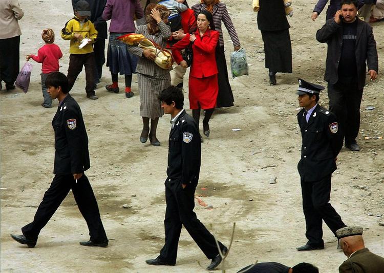 Sikkerhedsvagter patruljerer på søndagsmarkedet i Xinjian-provinsens hovedby, Hotan. 