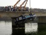 Den forulykkede bus hæves op på broen over Narmada-kanalen nær byen Bodeli omkring 180 kilometer syd fro Ahmadabad i Indien. 
