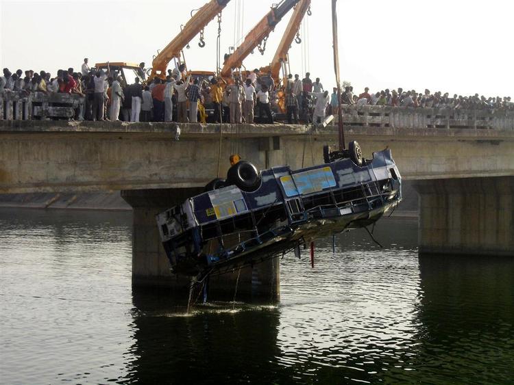 Den forulykkede bus hæves op på broen over Narmada-kanalen nær byen Bodeli omkring 180 kilometer syd fro Ahmadabad i Indien. 