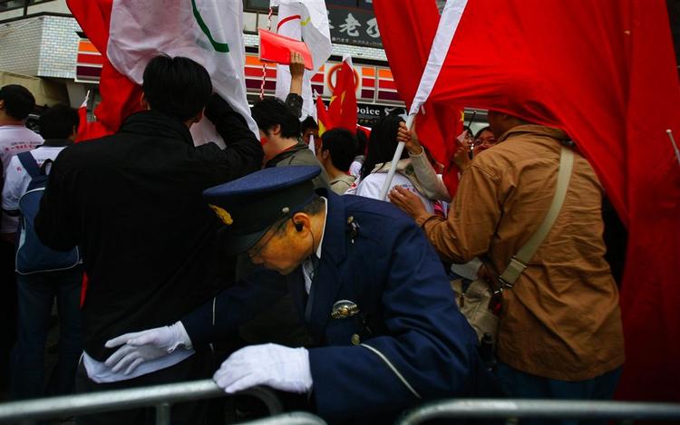 En japansk betjent forsøger at kæmpe sig vej gennem en demonstration i Nagano. 