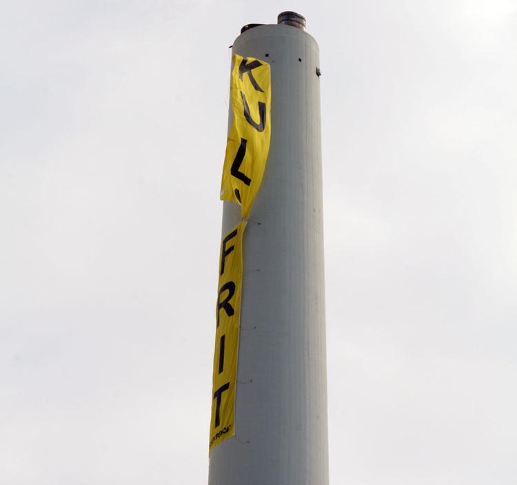 De fire sidste Greenpeace-aktivister har forladt skorstenen i Avedøre. På billedet er de ved at tage deres 35 meter lange banner ned. 