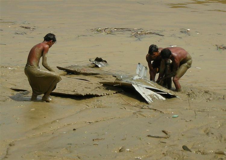 Situationen i Myanmar er desperat, siger Dansk Røde Kors mand i landet, Anders Ladekarl. Her forsøger en gruppe mænd at redde resterne af et hus fra mudderet langs Yangon-floden. 