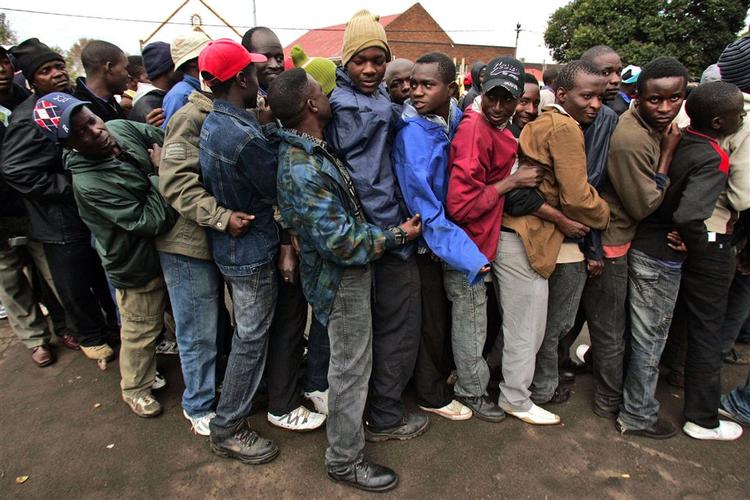 Immigranter i Sydafrika står i kø for at få mad i en midlertidig flygtningelejr. 