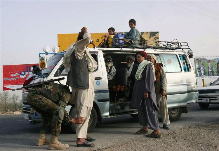 En afghansk soldat undersøger civile, der er på vej ud af Arghandab. 