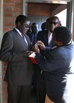 Robert Mugabe får tjekket sin finger for det blæk, som alle vælgere får på, så man kan se, om de har stemt. 