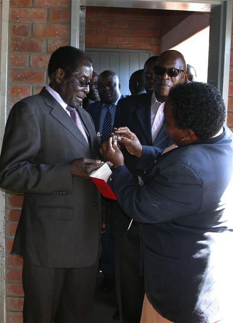 Robert Mugabe får tjekket sin finger for det blæk, som alle vælgere får på, så man kan se, om de har stemt. 
