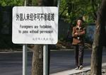 En indbygger i Beijing går forbi et skilt, der skal holde OL-gæsterne væk fra et militært område. 