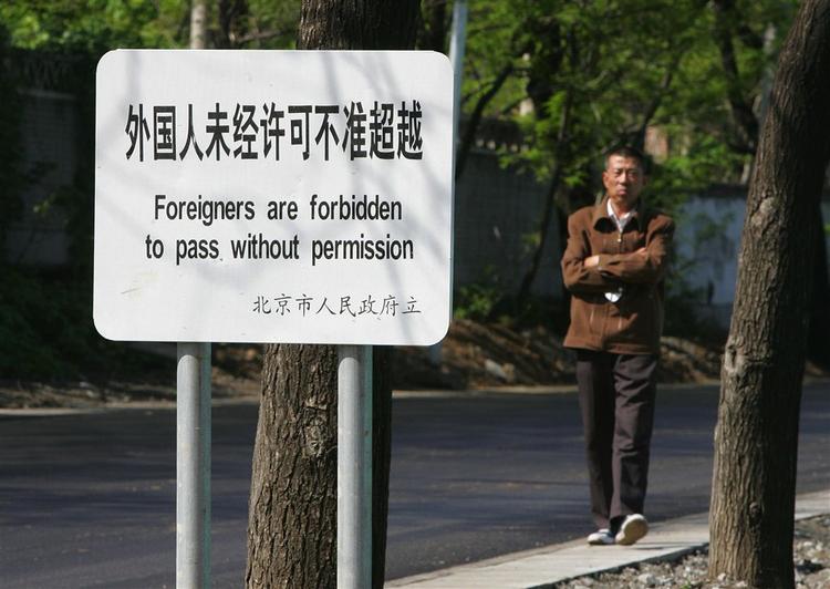 En indbygger i Beijing går forbi et skilt, der skal holde OL-gæsterne væk fra et militært område. 