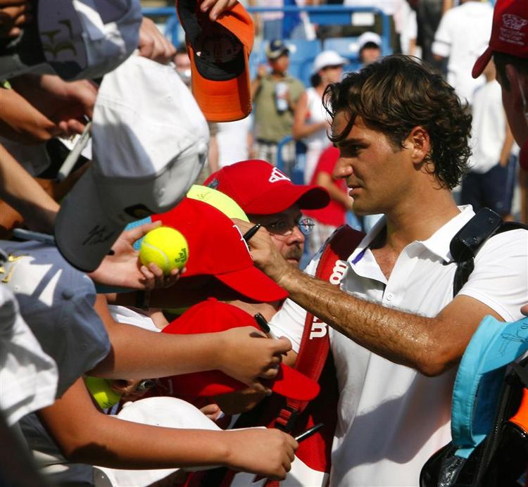 Roger Federer skriver autografer efter sejren i åbningskampen i Cincinnati. 