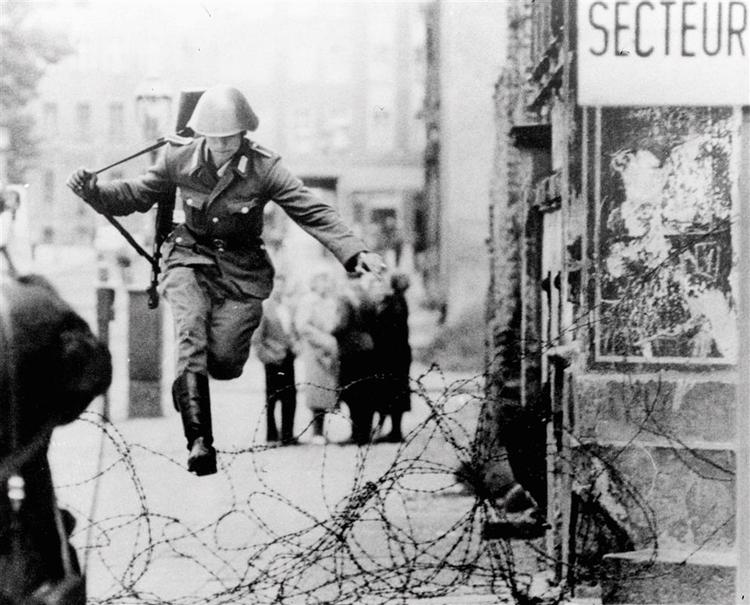 !5. august 1961. En østtysk grænsesoldat flygter over Berlinmuren, mens han kan. Siden blev hundredvis af civile skudt, da de forsøgte at flygte. 