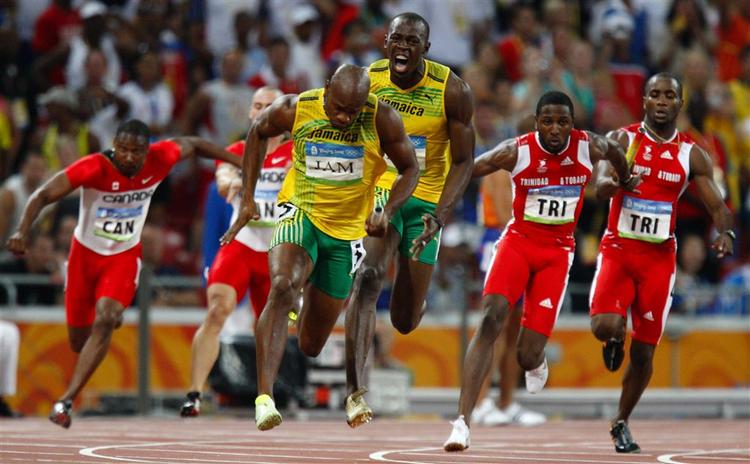 Jamaicas Usain Bolt sender holdkammeraten Asafa Powell af sted på den sidste strækning mod guldet og verdensrekorden. 