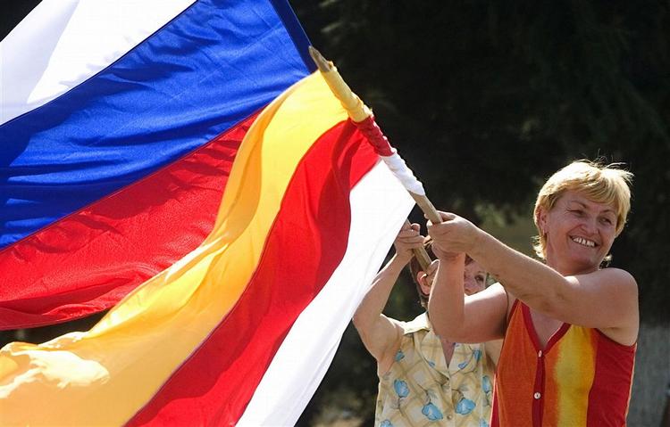En ossetisk kvinde svinger med både det russiske ogm det syd-ossetiske flag efter meddelsen om den russiske anerkendelse. 
