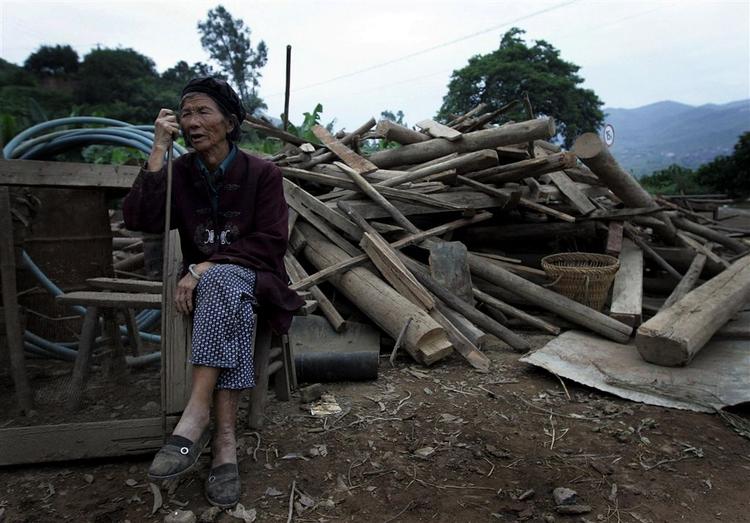 En ældre kinesisk kvinde sidder ved siden af sit ødelagte hus efter det jordskælv, der lørdag ramte Kinas Sichuan-provins. 