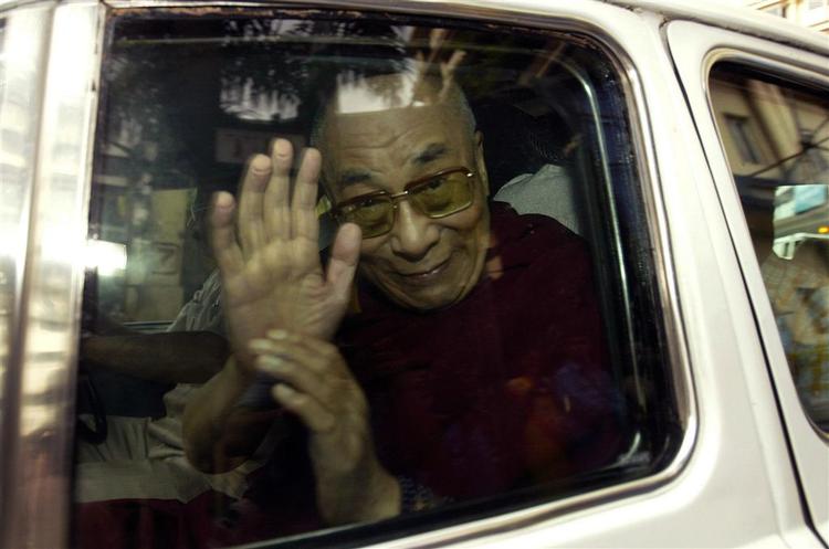Dalai Lama vinker fra bilen, da han kører væk fra hospitalet i Mumbai. 