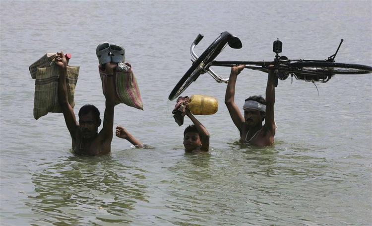 Landsbybeboere flygter i sikkerhed fra de kraftige oversvømmelser i Indien. 
