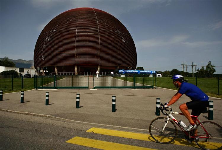 En cyklist passerer indgangen til denne globe af træ. Verdens største fysikforsøg vil finde sted under jorden. 