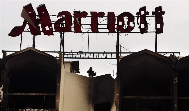 Det luksuriøse Hotel Marriott i Islamabad er stort set udbrændt. Oprydningsarbejdet er i gang. Her patruljerer en politimand på hotellets tag. 