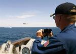 En officer på et amerikansk krigsskib holder øje med 'Faina', som ses i det fjerne. 