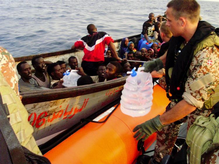 De næsten 40 somaliske bådflygtninge blev standset af Absalon og fik udleveret mad og drikke. Flygtningene håber at nå til Yemen og har på denne position kun små to timers sejltur tilbage i ders skiff-båd. Marinekonstabel Ole Jensen rækker vand over til de tørstige somalier.Foto: Frank Hvilsom 