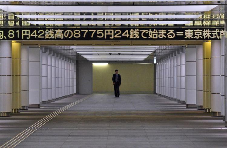 En fodgænger i Tokyo går i dag under et display, der bringer nyheden om, at aktiemarkederne åbnede med en kraftig stigning. 