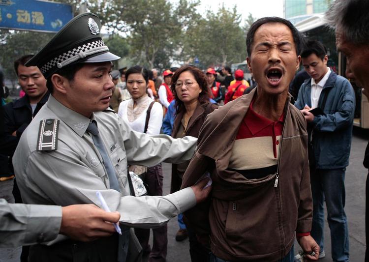 Manden til højre blev ifølge Associated Press anholdt for at have spyttet på gaden i millionbyen Hangzhou i oktober 2007. Nye tal viser nu, at OL har haft en opdragende effekt. 
