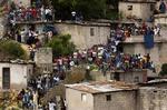 Bekymrede haitianere kigger på, mens redningsfolk leder efter overlevende i ruinerne efter den skole, som styrtede sammen fredag. 