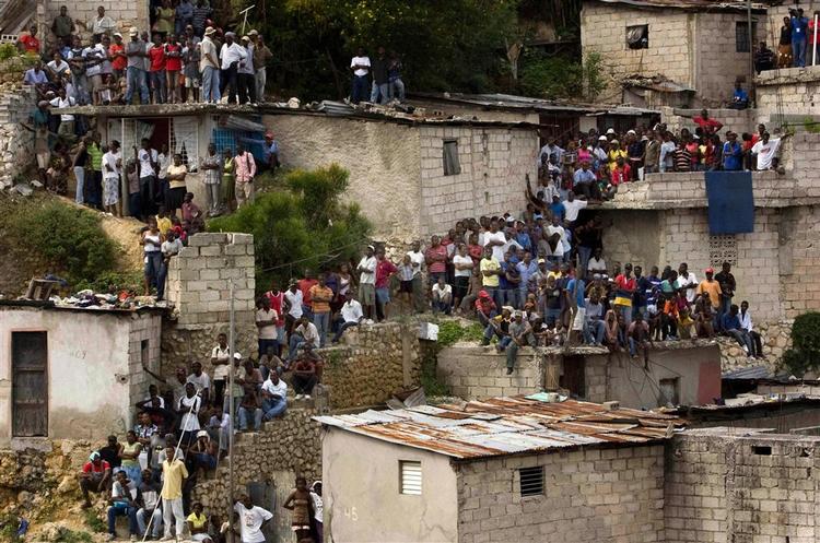 Bekymrede haitianere kigger på, mens redningsfolk leder efter overlevende i ruinerne efter den skole, som styrtede sammen fredag. 