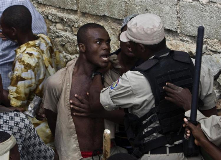 Politibetjent holder pårørende væk fra den sammenstyrtede skole i Haiti. 