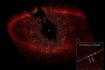 Den hvide prik i midten er stjernen Fomalhaut. To hvide prikker nederst til højre i billedet viser planeten Fomalhaut b's position i 2004 og 2006 - planetens rejse rundt om sin sol varer 872 jordår. I alt er skyen af materiale omkring solen 34,5 milliarder kilometer på tværs. 