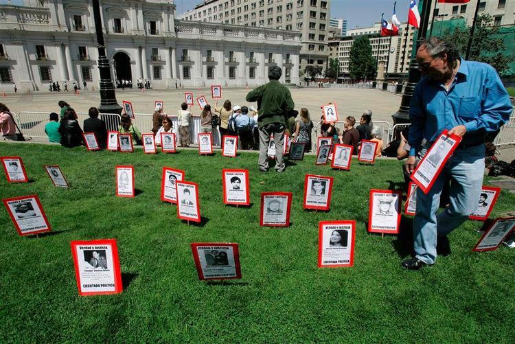 Slægtninge til ofre for diktaturregimet under general Augusto Pinochet placerer fotos af deres forsvundne familiemedlemmer foran præsidentpaladset i Santiago, Chile 30. oktober i år. Arkivfoto. 