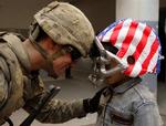 En amerikansk soldat på besøg på en irakisk skole i Mosul. Drengen er iklædt en football-hjelm svøbt i det amerikanske flag. 