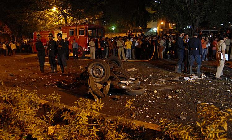 Indere står omkring et ødelagt køretøj i Mumbai efter terrorangrebet. 