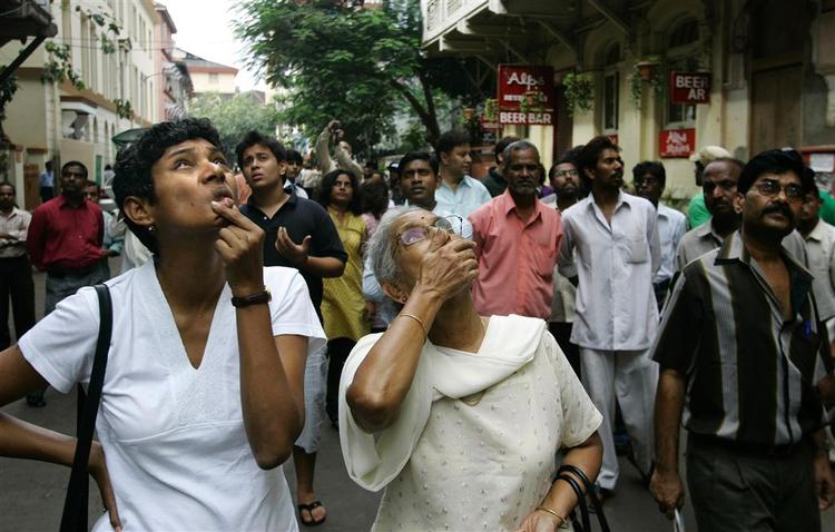 Indbyggere i Mumbai kigger op på det stærkt beskadigede Taj Mahal-hotel, hvor et gidseldrama stod på i 60 timer. 