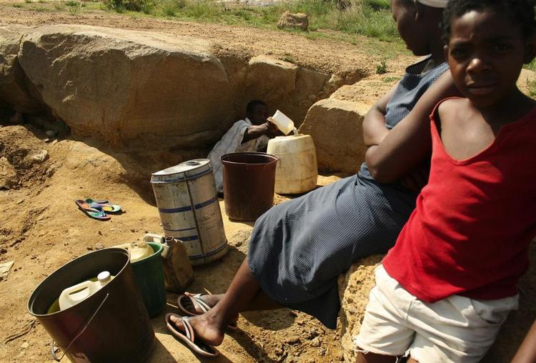 En mand forsøger at få fat i noget rent vand fra en brønd i Zimbabwes hovedstad Harare. 