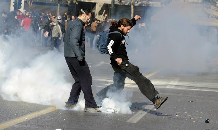 Græske demonstranter sparker tåregas tilbage til politiet foran parlamentsbygningen i det centrale Athen i dag. 