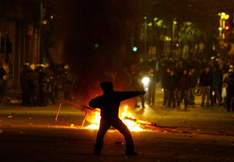 En ung mand kaster sten efter uropoliti uden for det tekniske universitet i midten af Athen i dag. 