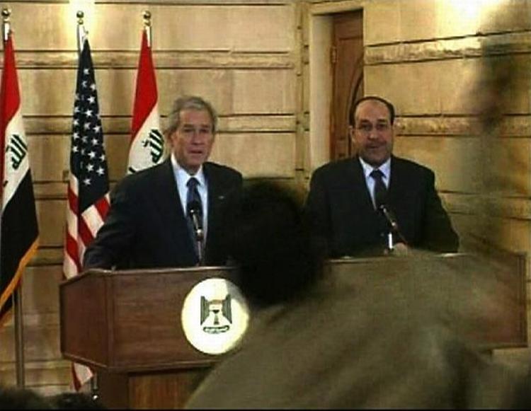 USA's præsident lige før han dukker sig for skoen. Iraks premierminister Nouri al-Maliki står uberørt under affyringen af begge sko. 