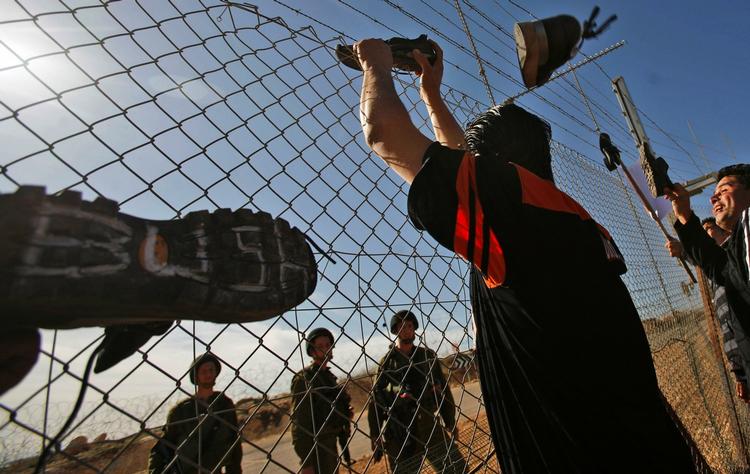 Palæstinensere kaster med sko mod israelske soldater ved Israels mur på  Vestbredden. 