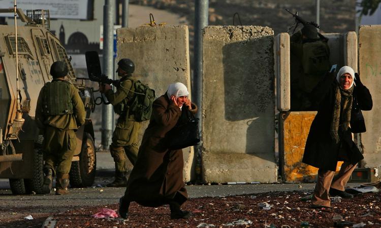 Palæstinensiske kvinder på grænsen mellem Ramallah og Jerusalem flygter fra sammenstød mellem israelske soldater og palæstinensiske demonstranter, der protesterer mod Israels angreb på Gaza-striben. 