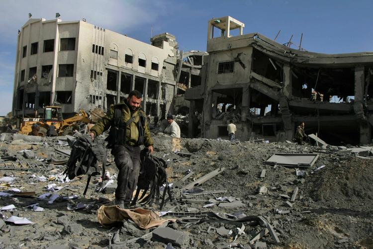 Et medlem af Hamas går forbi en offentlig bygning, der blev ramt af det israelske luftangreb. 