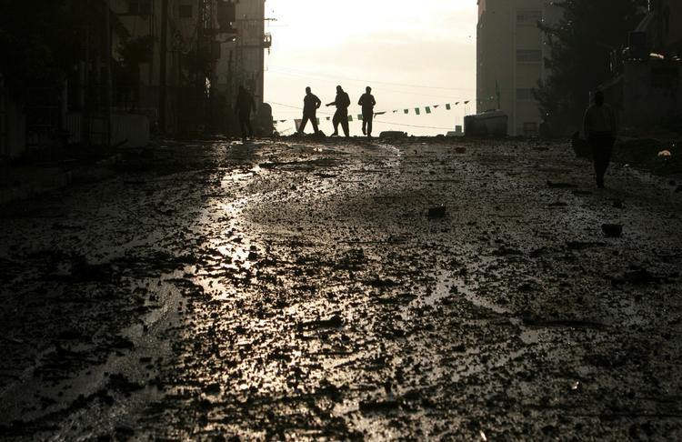 Palæstinensere krydser en gade i Gaza By, hvor det israelske luftangreb har ramt Hamas' regeringsbygninger. 