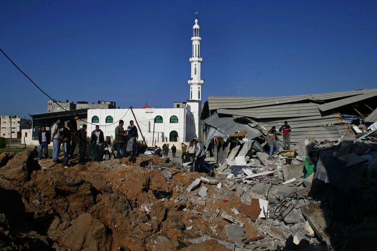 Israelerne har i nat og i dag fortsat de massive bombeangreb i Gaza. Billedet her er fra i går, hvor palæstinensere betragter ødelæggelserne efter et angreb i flygtningelejren Rafah i den sydlige del af Gazastriben. 
