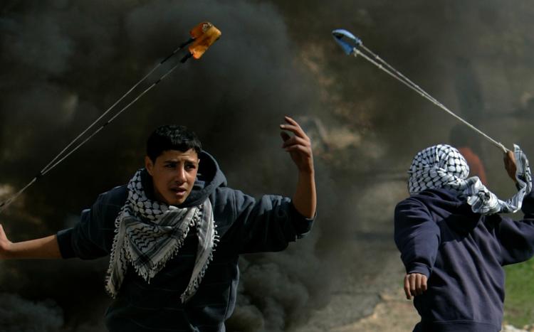 Hamas afviser at indgå våbenhvile, sådan som FN-resolution kræver det. På billedet ses demonstranter på Vestbredden, der kaster sten efter israelske soldater nær Ramallah. 