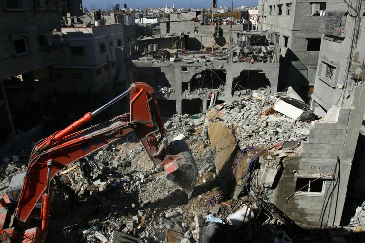 En bulldozer rydder brokkerne af et privat hjem, som er pulveriseret af et israelsk flyangreb. Her døde blandt andet Kaukab al Dayah, en fireårig palæstinensisk pige. Mindst 250 palæstinensiske børn er dræbt af angrebene indtil videre. 