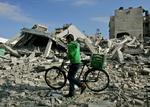 En ung palæstinenser trækker sin cykel over ruinerne af Fatah-lederen Mohammed Dahlans bolig der er blevet ramt af et missil. 