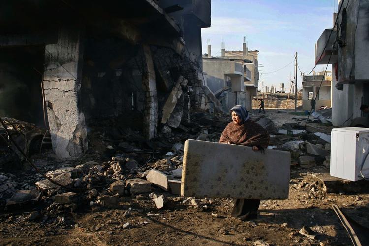 En palæstinensisk kvinde har fundet en madras i resterne af en udbombet bygning i Rafah. I området boede flere Hamas-ledere, hvis huse er blevet totalt ødelagt. 