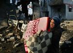 En kvinde bærer familiens ejendele   ud af ruinerene efter et bombardement mod Hamas huse i et tætbefolket område i Rafah. 