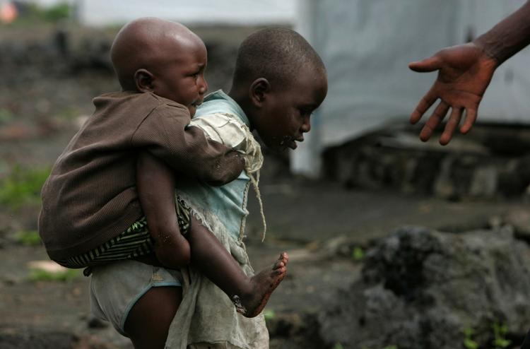 To flygtningebørn forcerer mudderet i en af Afrikas mange flygtningelejre. Arkivfoto. 